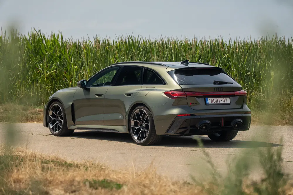 Groene Audi RS6 Avant op landweg voor maïsveld, zwarte sportvelgen.