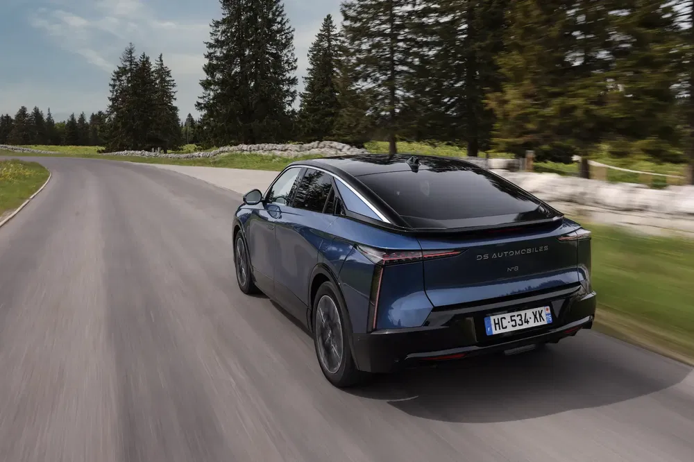 DS Automobiles DS 9 rijdt op kronkelige weg omringd door bomen.