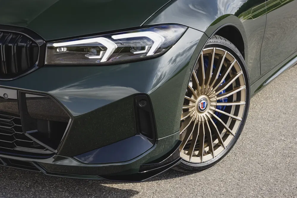 Gros plan avant d'une BMW Alpina avec jante dorée élégante sur route.
