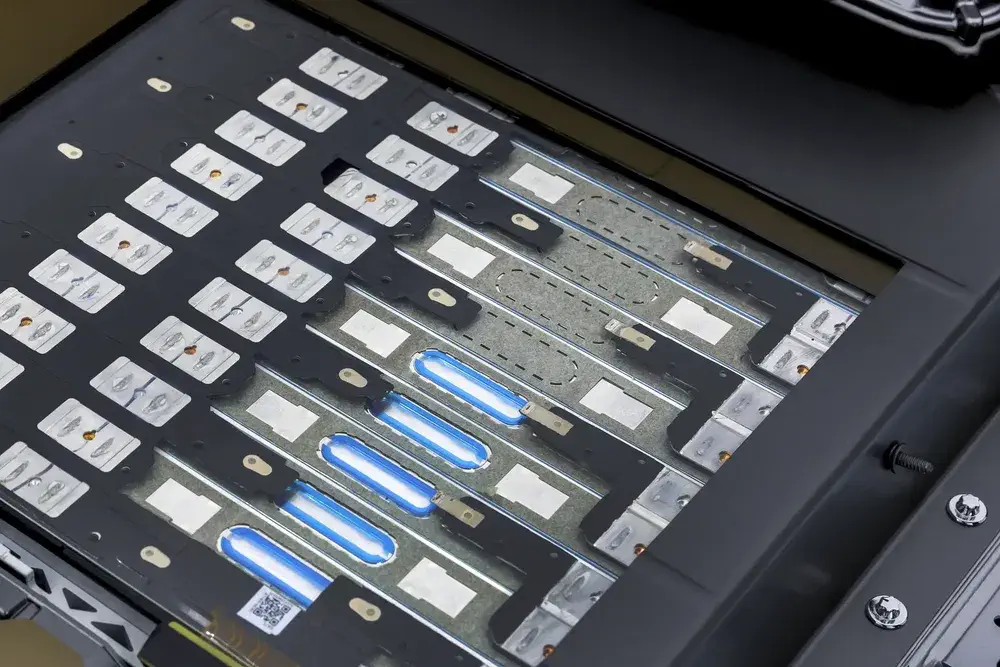 Module de batterie de véhicule électrique avec cellules visibles et éclairage LED bleu.
