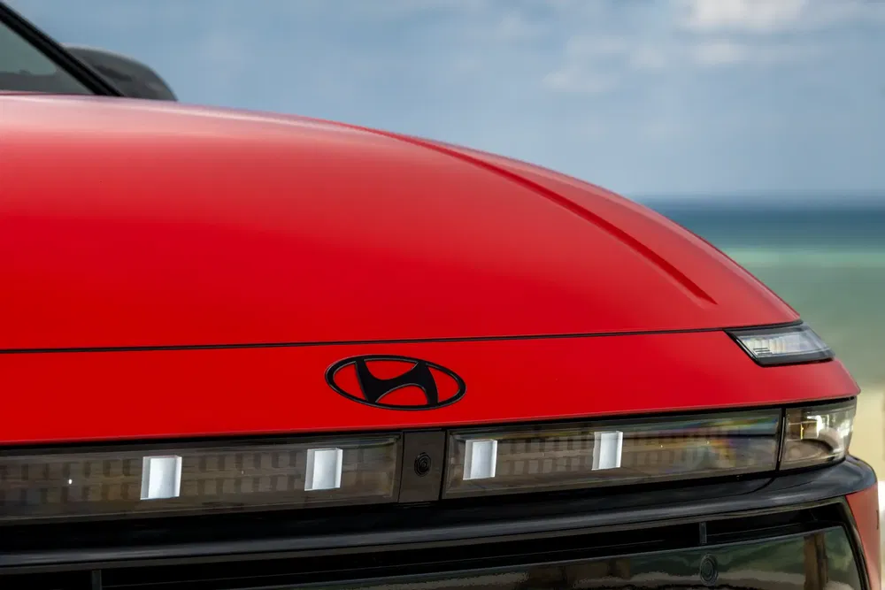 Close-up van een rode Hyundai met moderne koplamp aan zee.