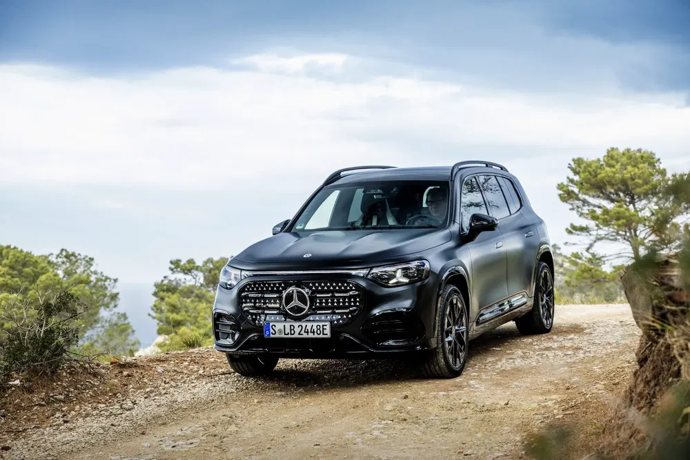 Mercedes-Benz GLC avance sur chemin de terre, forêt en arrière-plan.