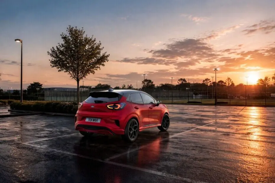 Ford Puma rouge garée au coucher du soleil sur un parking humide.