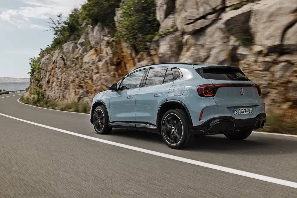 Mercedes-Benz SUV op kronkelige weg, omgeven door rotsen en begroeiing.