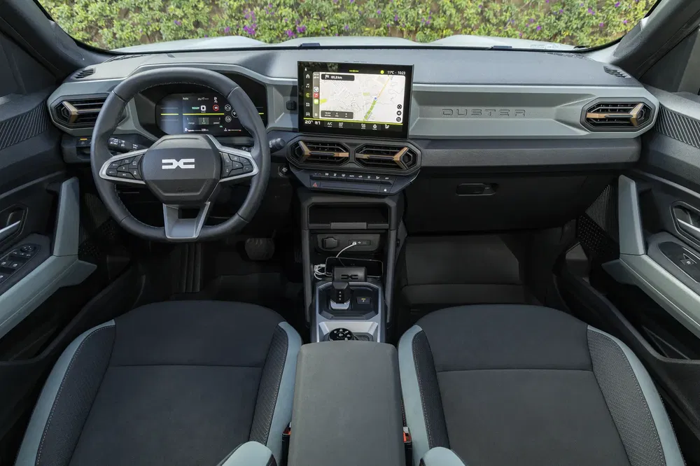 Interieur van de nieuwe Dacia Duster met touchscreen, modern stuurwiel en ergonomische stoelen.