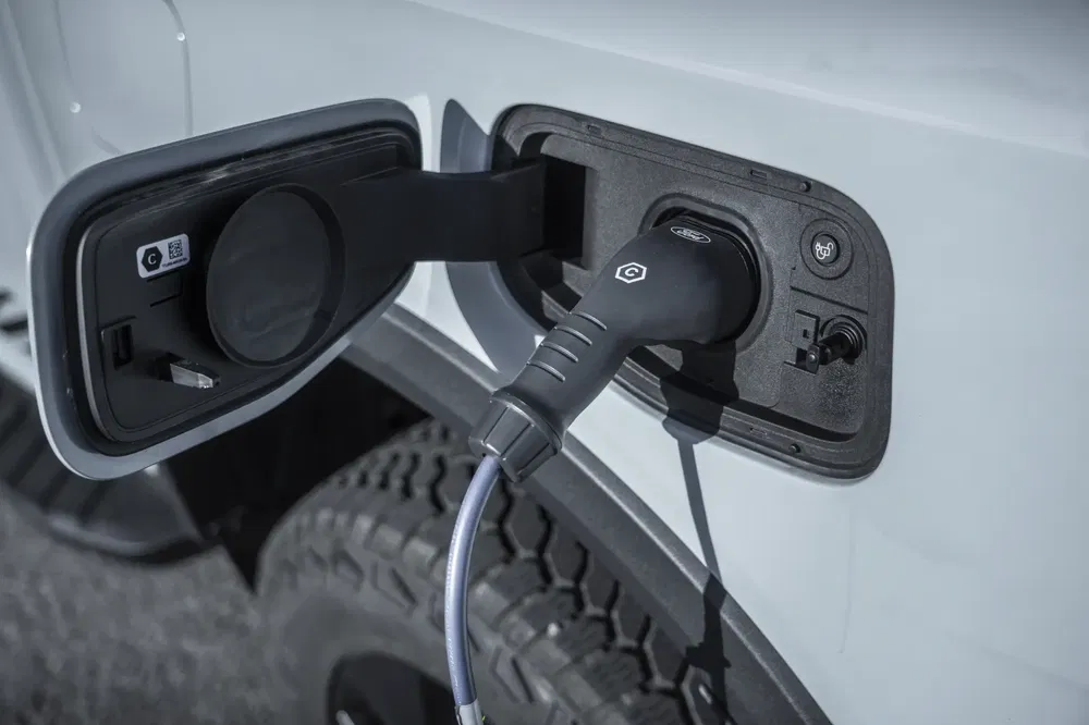 Elektrische Ford auto in opladen, stekker aangesloten op witte auto-aansluiting.