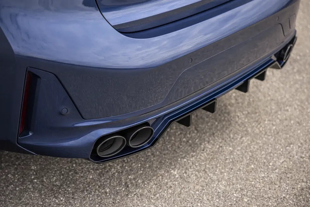 Arrière de BMW M4 bleu avec quadruple échappement et diffuseur aérodynamique.