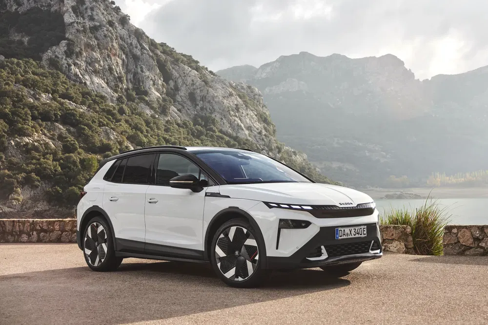 SUV blanc moderne sur fond de montagnes et lac paisible, design aérodynamique élégant.