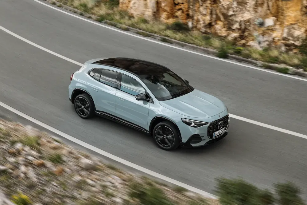 Mercedes-Benz EQA rijdend op een bochtige weg naast rotsachtige kliffen.