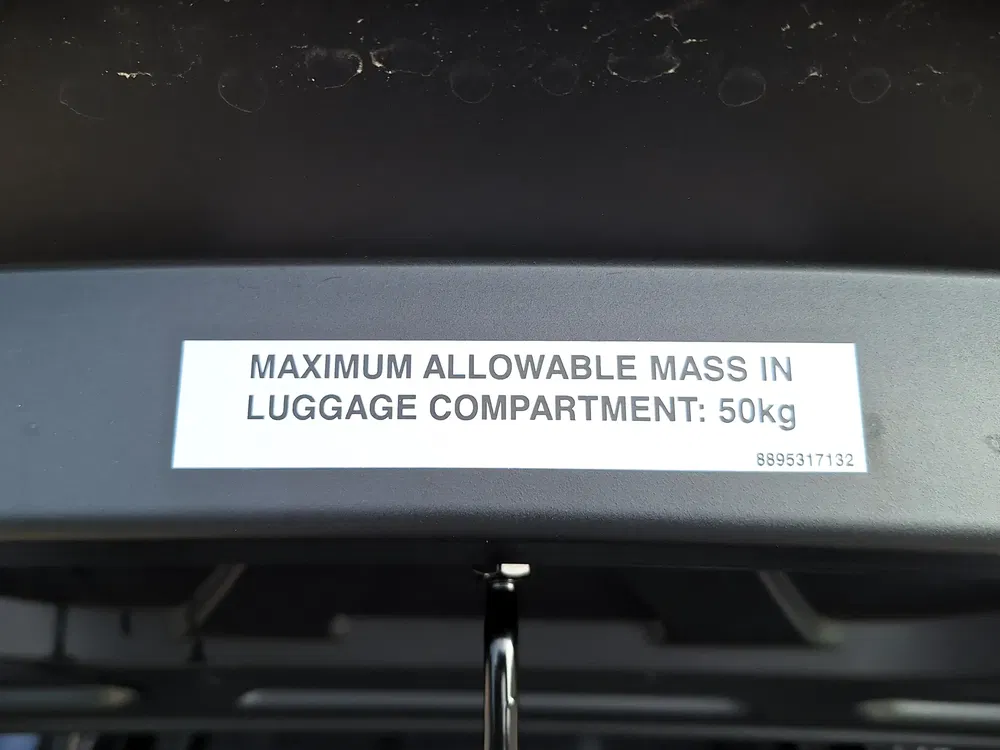 Sticker met maximale toegestane massa van 50 kg in de kofferbak van de auto.