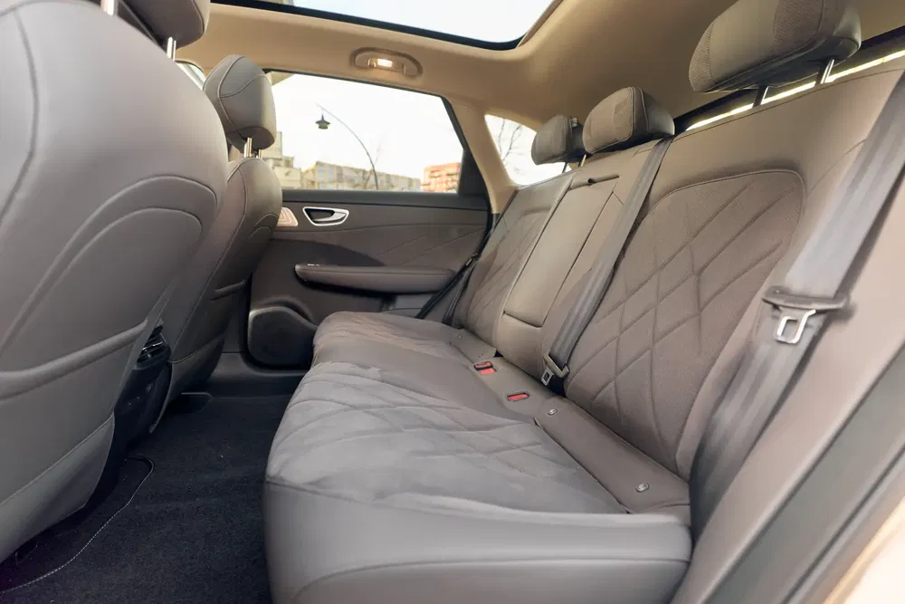 Intérieur spacieux, sièges arrière en cuir beige, toit panoramique d'une berline haut de gamme.