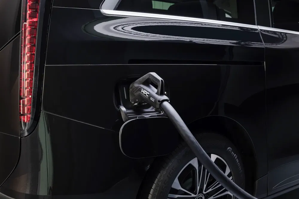 Voiture électrique noire en chargement rapide avec câble HPC branché à l'arrière.