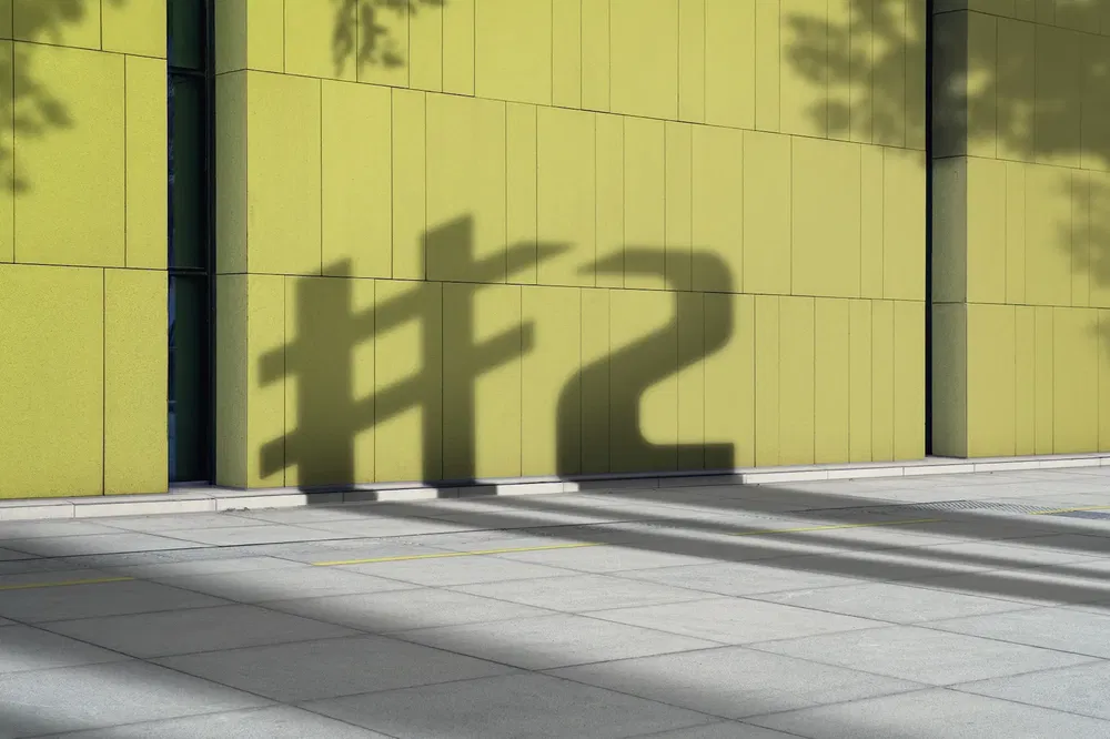 Ombre de #2 projetée sur un mur jaune moderne, inspirant la compétition automobile.