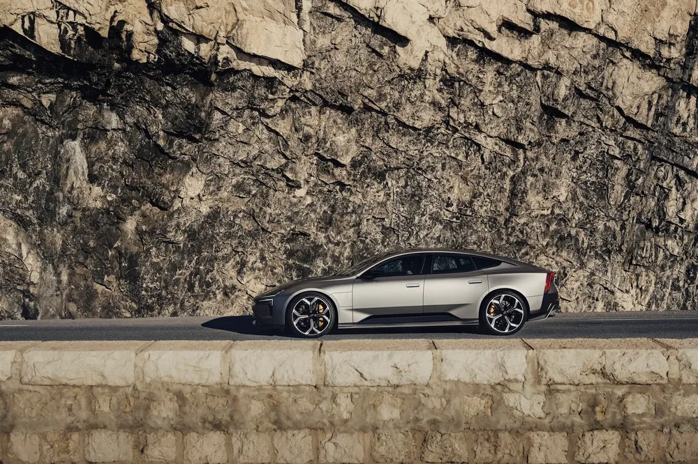 Zilveren Polestar 1 auto geparkeerd voor een imposante rotswand.