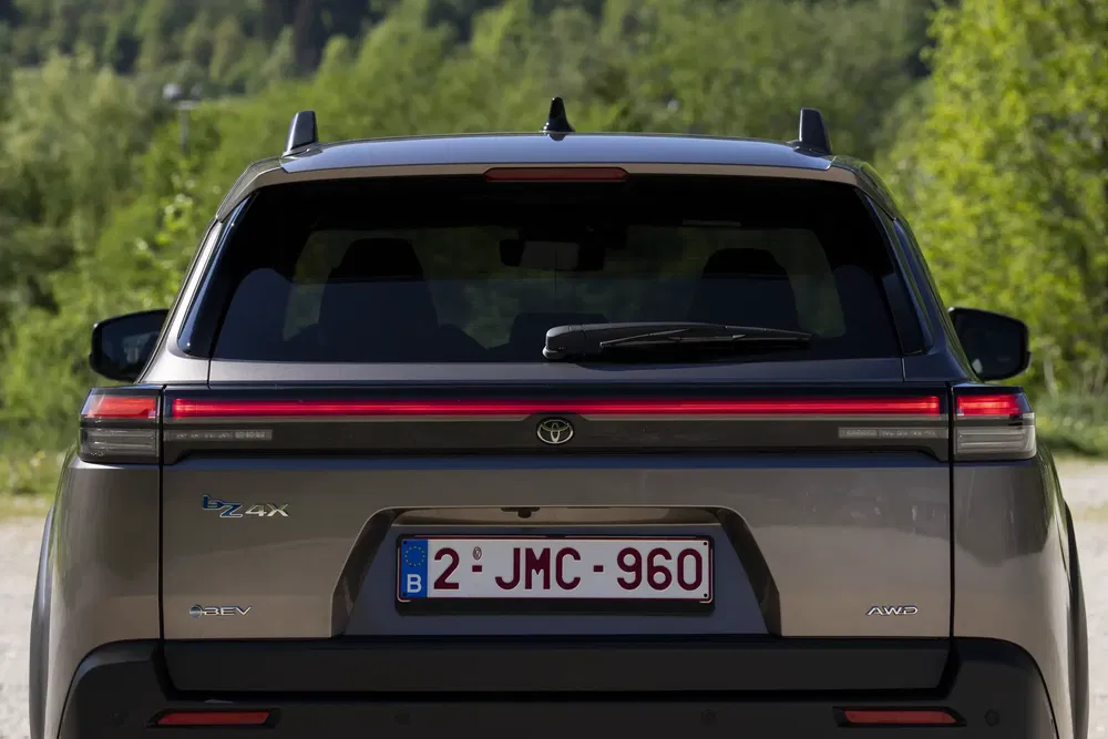 Toyota bZ4X électrique vue arrière dans un paysage verdoyant.