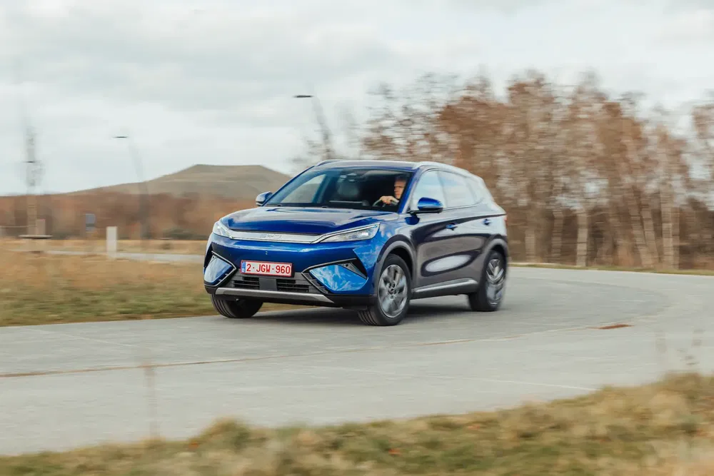 Elektrische MG SUV op kronkelende plattelandsweg in herfstlandschap.