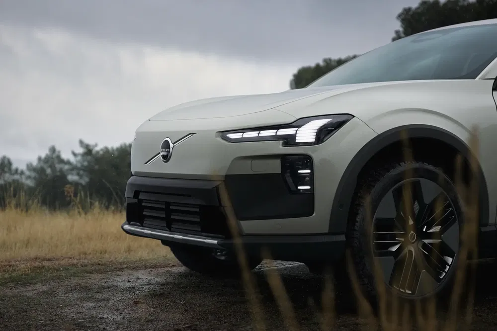 Volvo EX90 électrique sur terrain boueux sous ciel nuageux, design moderne et robuste.