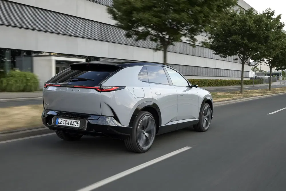 SUV électrique Lexus roulant en ville, vu de l'arrière, avec design moderne.
