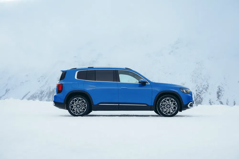 SUV bleu sur neige avec montagnes enneigées en arrière-plan, style moderne et élégant.
