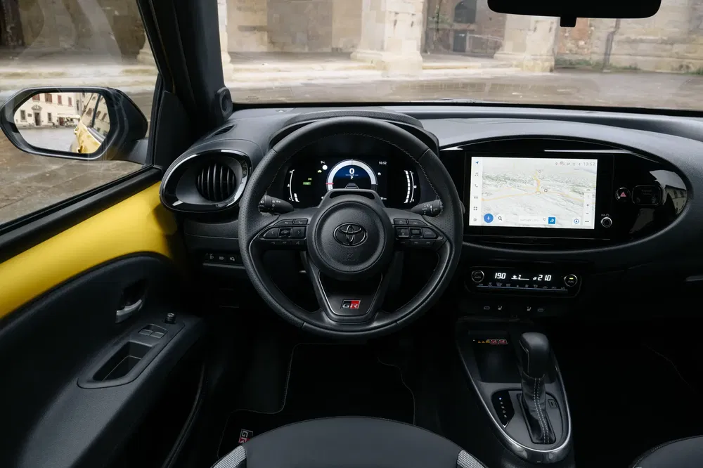Intérieur de la Toyota Aygo X avec tableau de bord numérique et écran de navigation.
