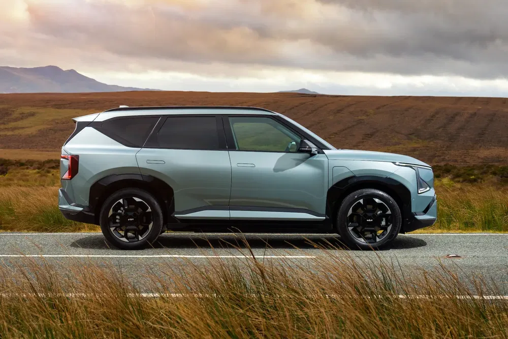 Moderne SUV op plattelandsweg met bewolkte lucht, slank ontwerp en opvallende zwarte wielen.