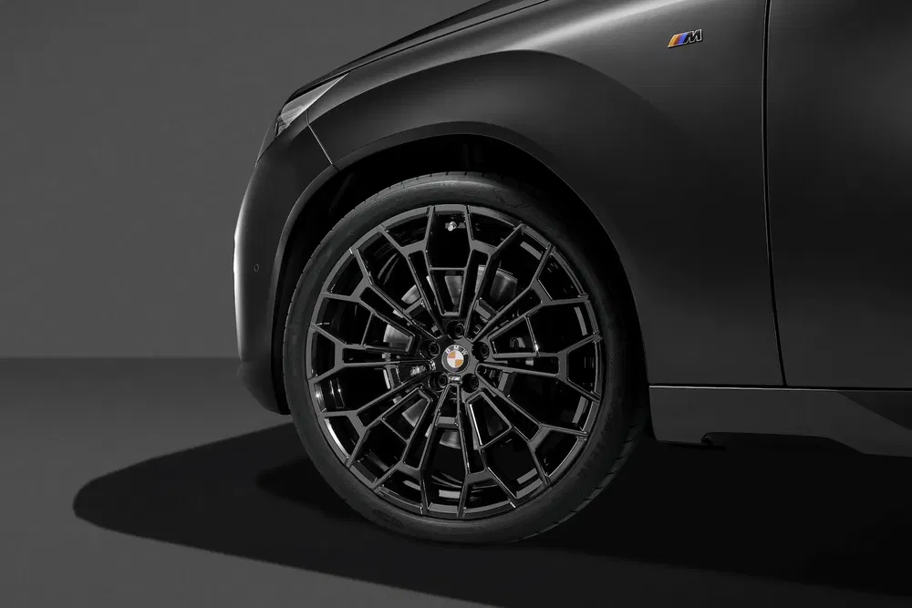Roue avant noire élégante sur une BMW avec badge M, en lumière sobre.