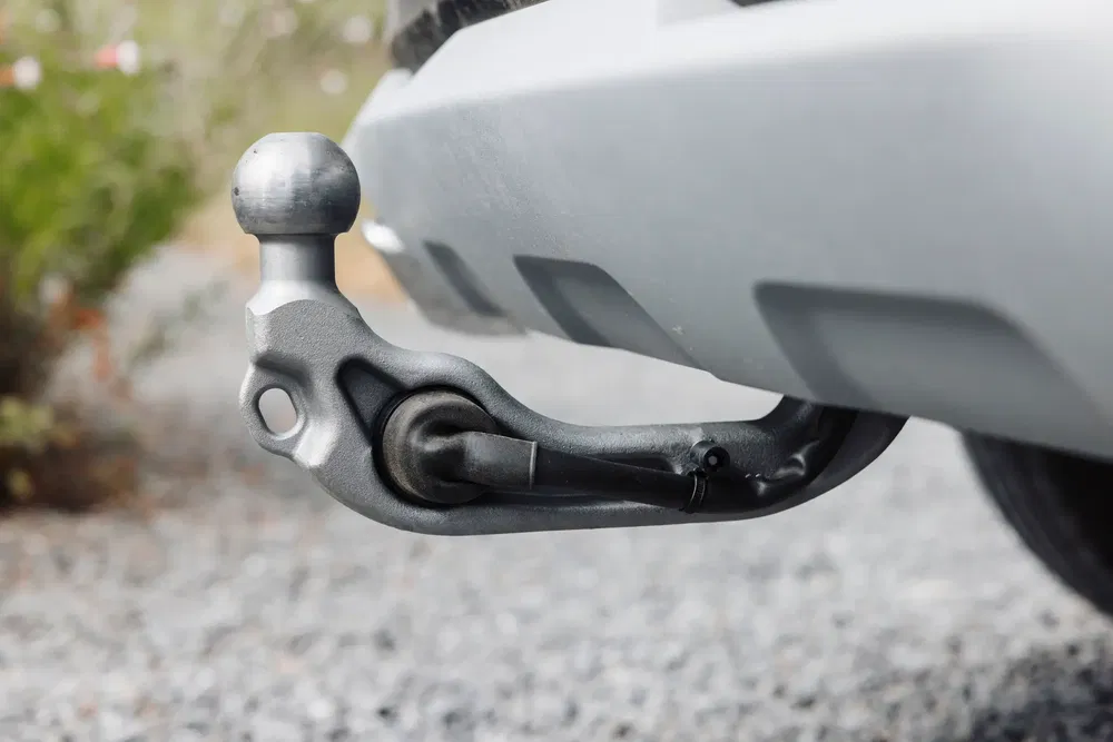 Attelage de remorque fixé à l'arrière d'une voiture sur chemin gravillonné.