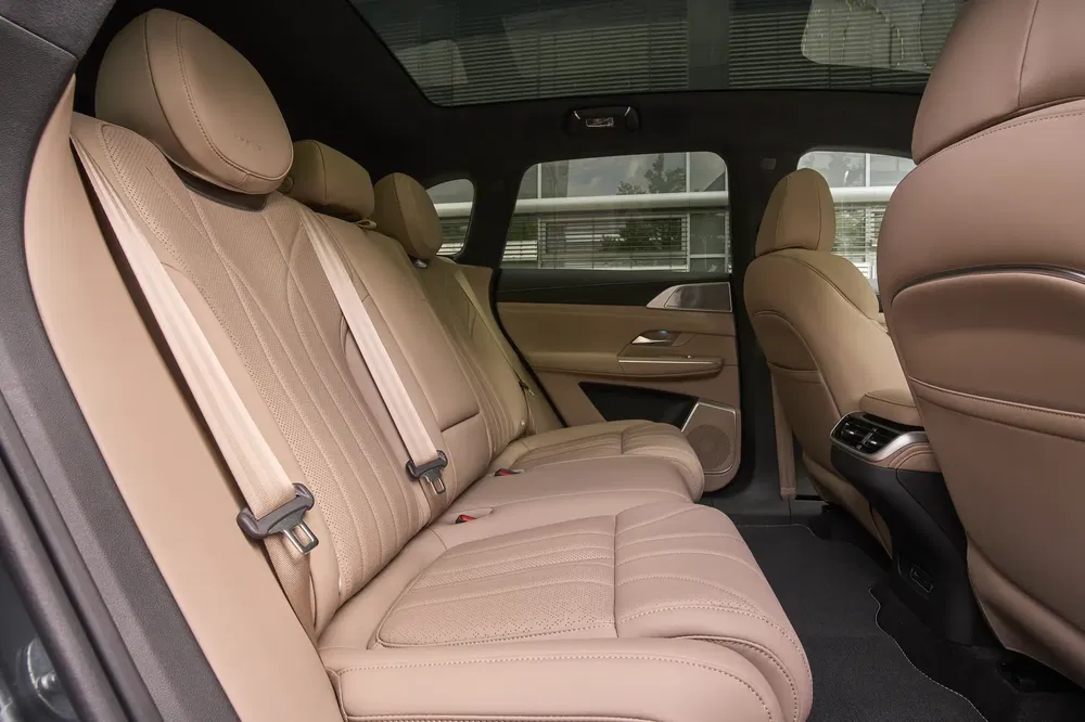 Ruime BMW X5 interieur, beige lederen achterstoelen, comfort en elegantie.