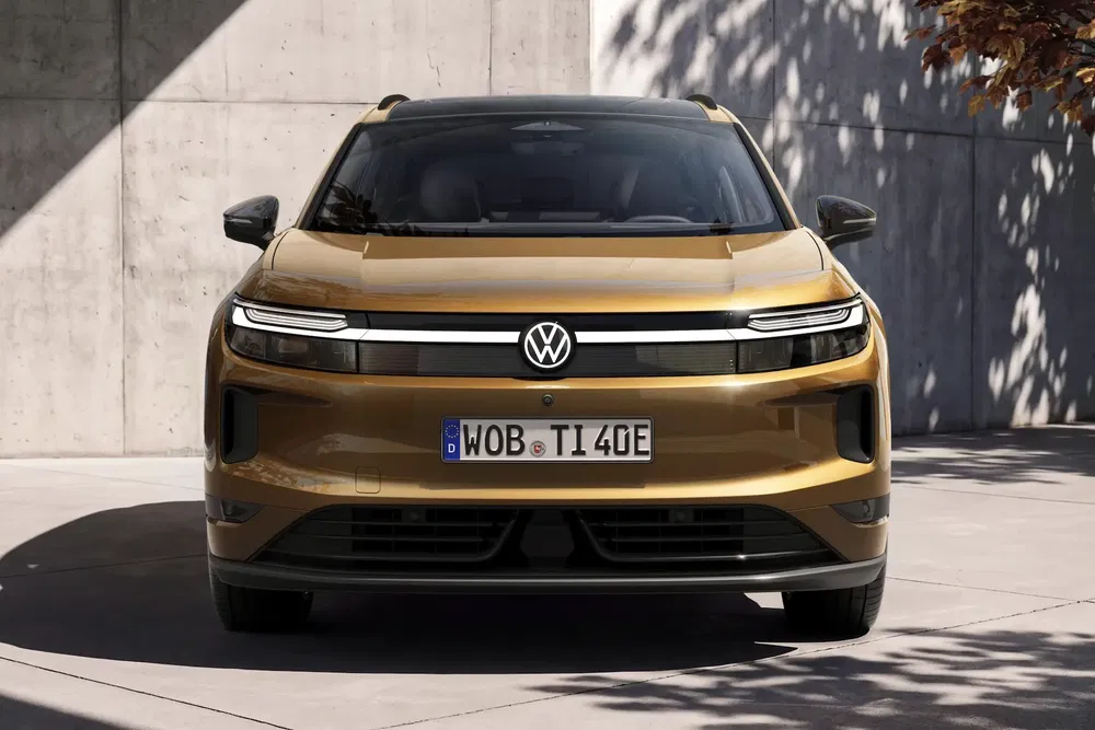 Vue avant du Volkswagen Tiguan 2024 doré, stationné devant un mur en béton.