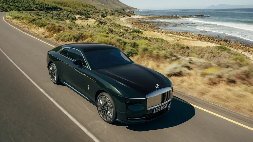 Voiture de luxe Rolls-Royce sur une route côtière panoramique avec vue sur l'océan.