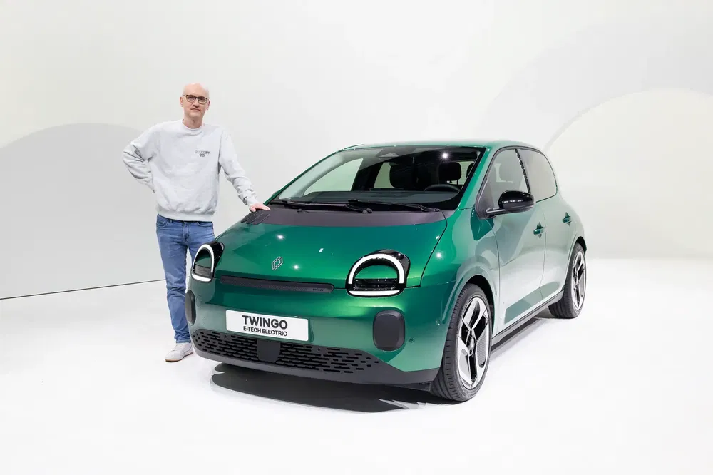 Renault Twingo électrique vert avec homme en arrière-plan, dans un studio bien éclairé.