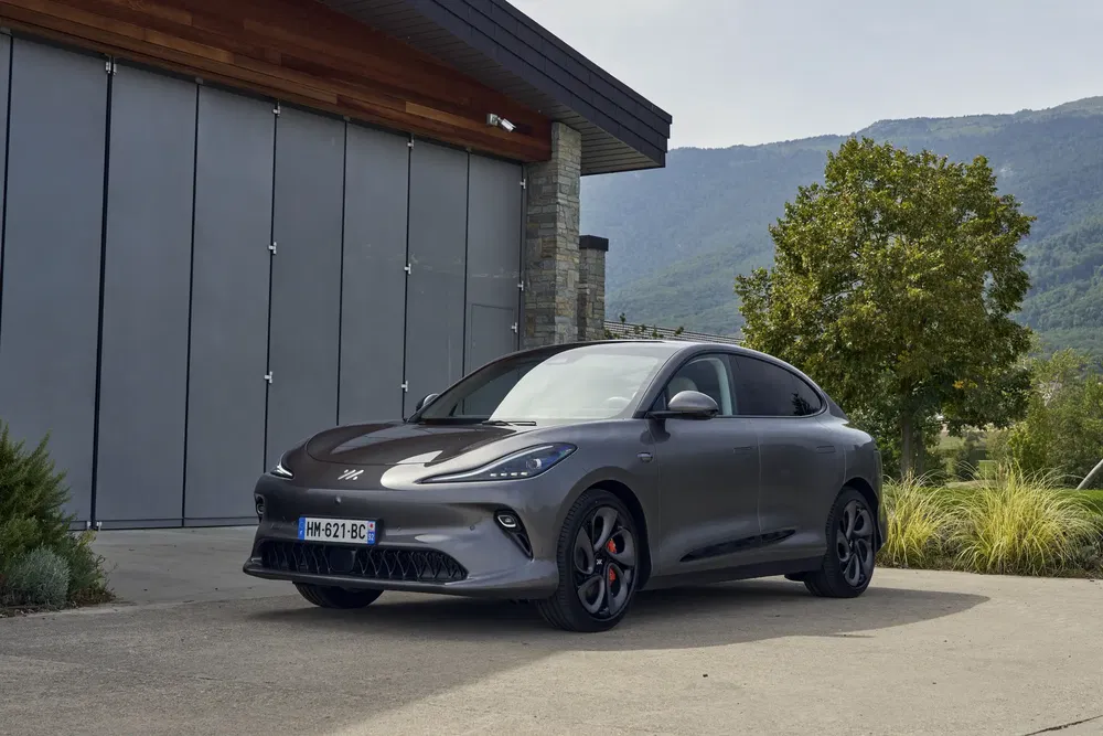 La voiture électrique MG, design moderne, garée devant un bâtiment industriel avec montagnes en arrière-plan.