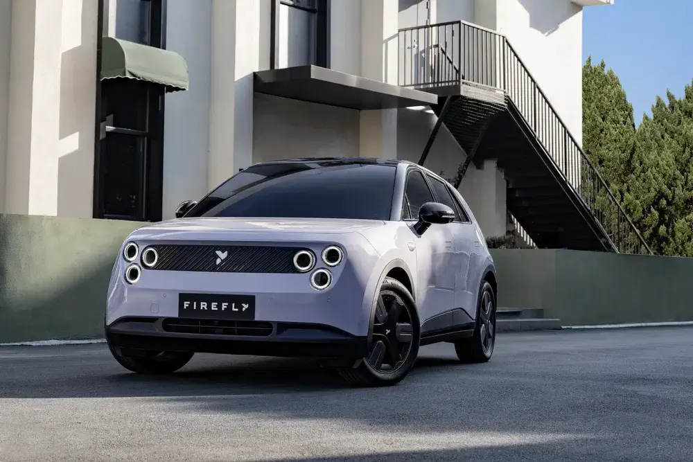 Moderne elektrische Firefly auto geparkeerd voor een gebouw, futuristisch en compact ontwerp.