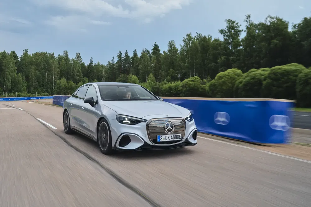 Mercedes-Benz gris sur circuit avec fond de forêt verdoyante.