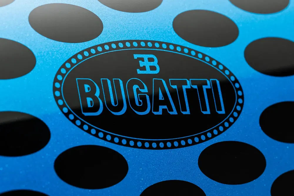 Logo Bugatti sur fond bleu à motifs noirs circulaires design moderne.