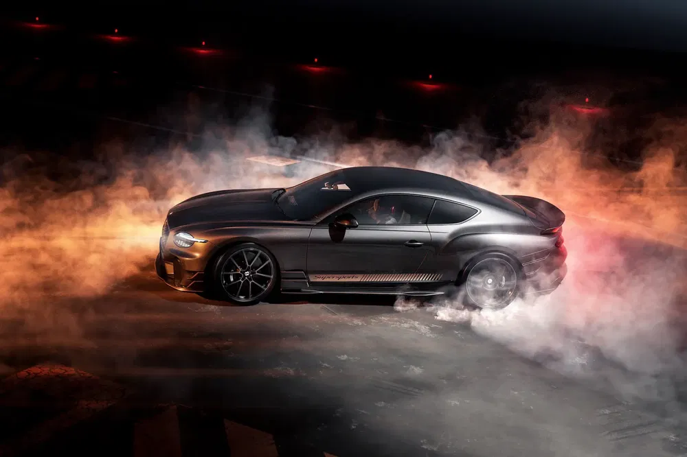 Ford Mustang GT effectuant un burnout avec de la fumée en arrière-plan dans un environnement sombre.