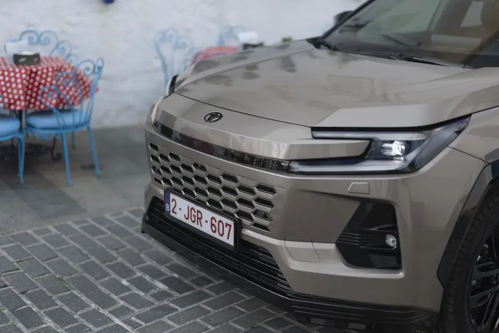 Moderne Hyundai SUV op kasseien, terras met kleurrijke tafels op achtergrond.