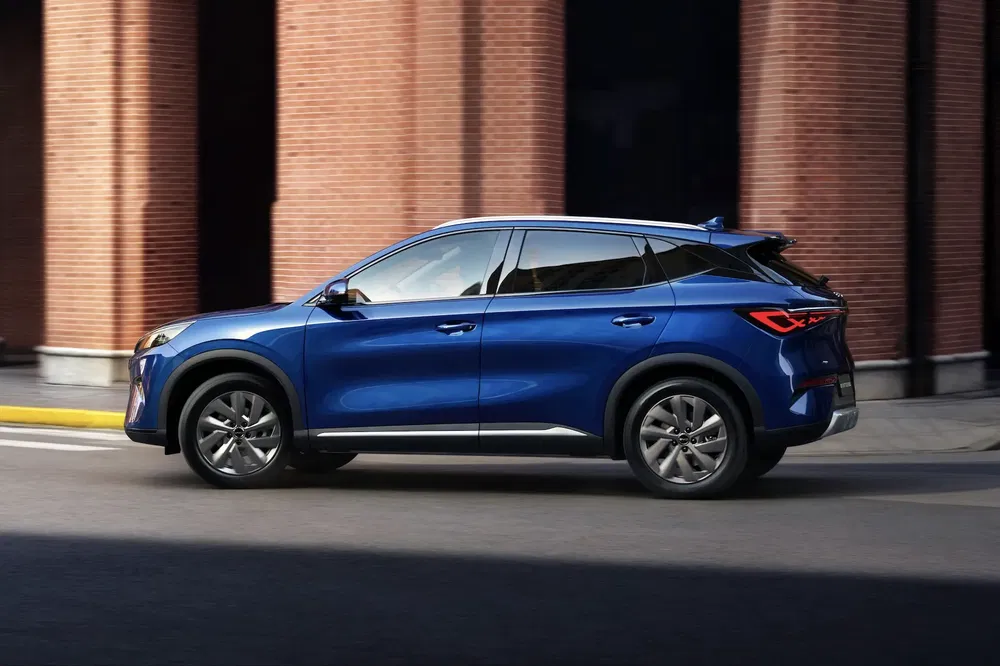 Blauwe MG SUV op stedelijke weg met bakstenen architectuur op achtergrond.