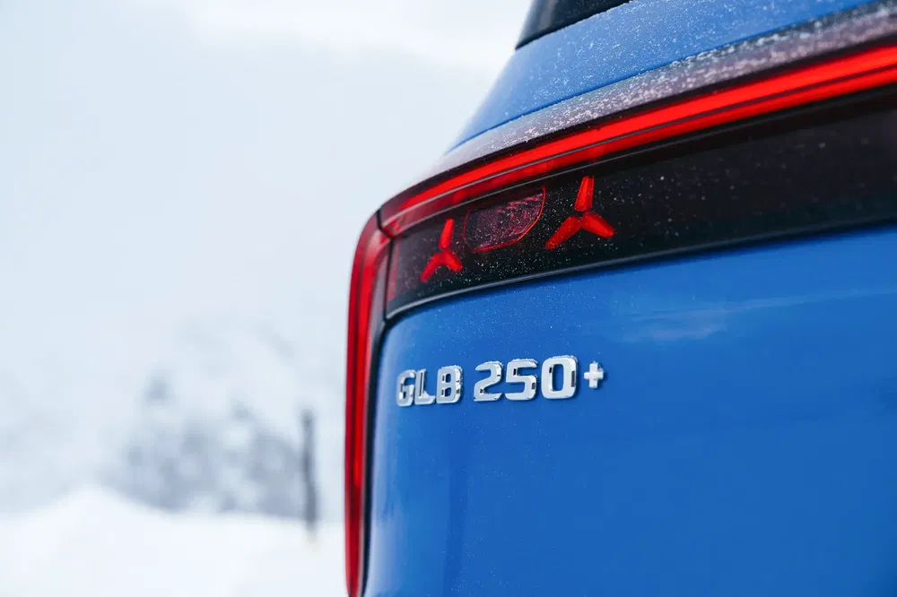 Vue arrière d'une Mercedes-Benz GLB 250+ bleue avec logo étoilé, en conditions hivernales.