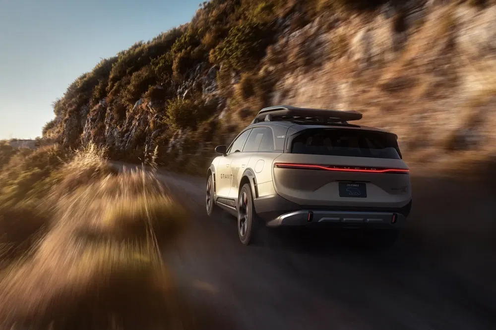 Lucid Gravity SUV sur route montagneuse avec éclairage arrière distinctif au crépuscule.