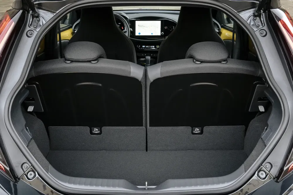 Coffre de Honda Jazz hybride, sièges arrière rabattus, affichage tableau de bord visible.