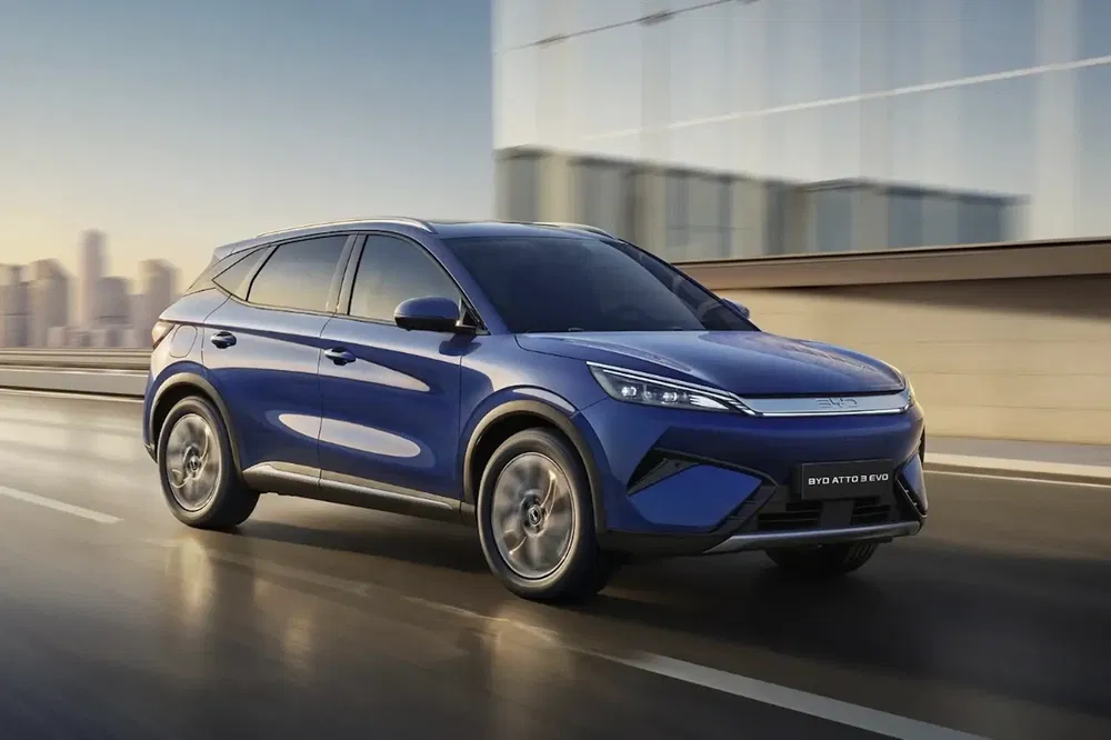 Blauwe BYD Atto 3 SUV rijdt snel op een stedelijke snelweg.
