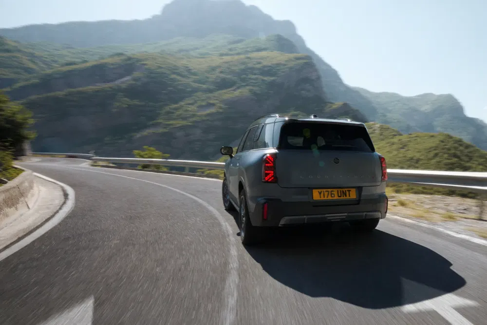 MINI Countryman gris roulant sur une route sinueuse de montagne par temps ensoleillé.