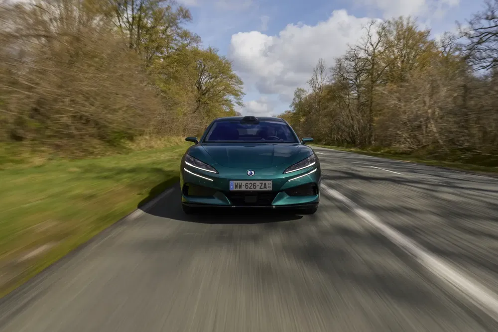 Elektrische DS-auto op met bomen omgeven weg, aerodynamisch ontwerp.