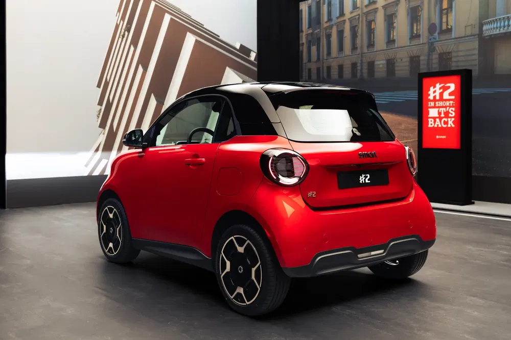 {"fr":"Compact Smart rouge dernier modèle dans un showroom moderne avec éclairage urbain.","nl":"Rode Smart compacte nieuwste model in een moderne showroom met stedelijke verlichting."}