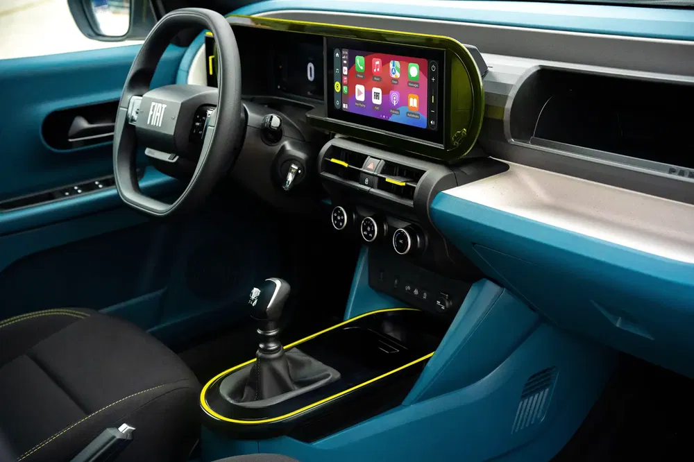 Intérieur moderne de Fiat avec écran tactile et volant ergonomique, finitions bleues et jaunes.