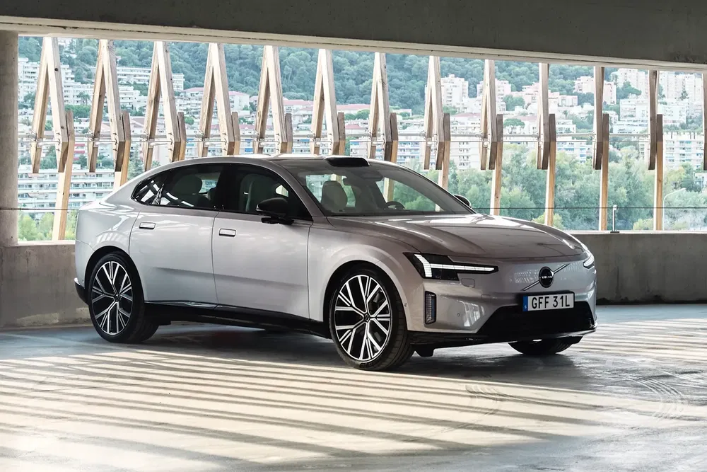 Volvo Polestar 2 argentée dans un parking avec vue sur la ville et montagne.