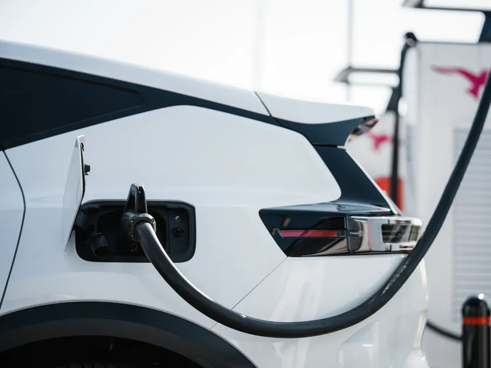 Elektrische auto aangesloten op een moderne laadstation, zicht van achteren.
