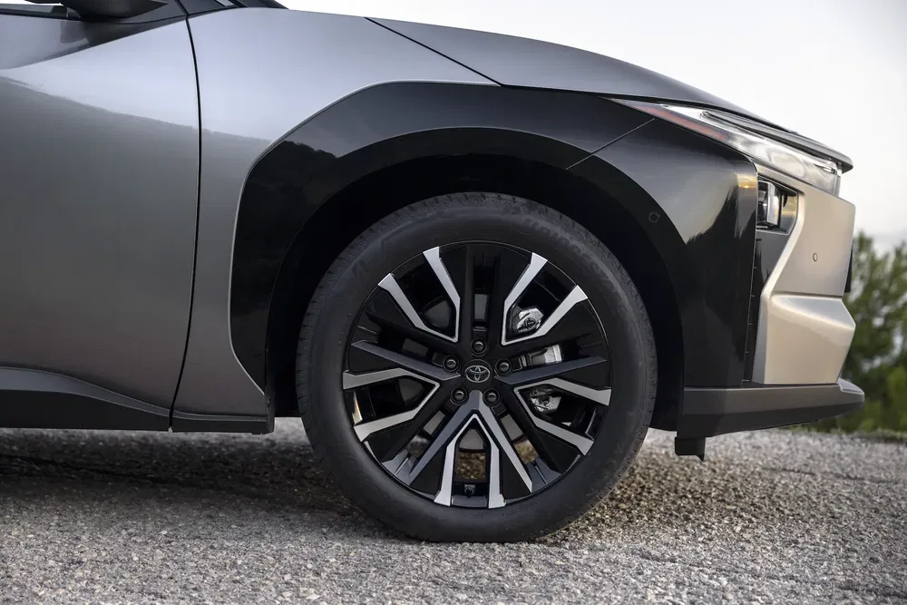 Detail van het voorwiel van de Toyota bZ4X op grindbodem.