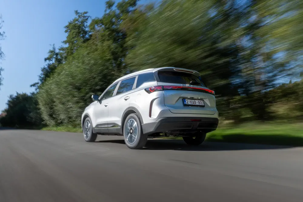 SUV argenté roulant sur la route, entouré de verdure luxuriante.